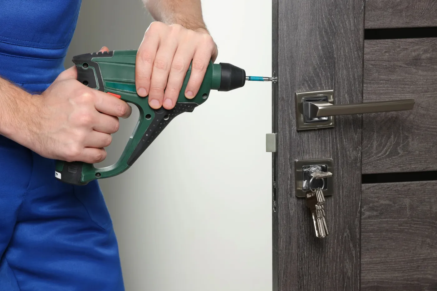 Serrurier vissant une serrure de sûreté sur une porte d'appartement à Paris 19e